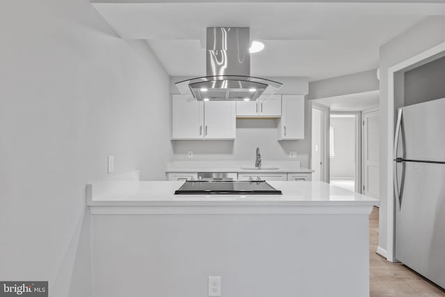 kitchen with white cabinetry, fridge, light wood-type flooring, island exhaust hood, and sink