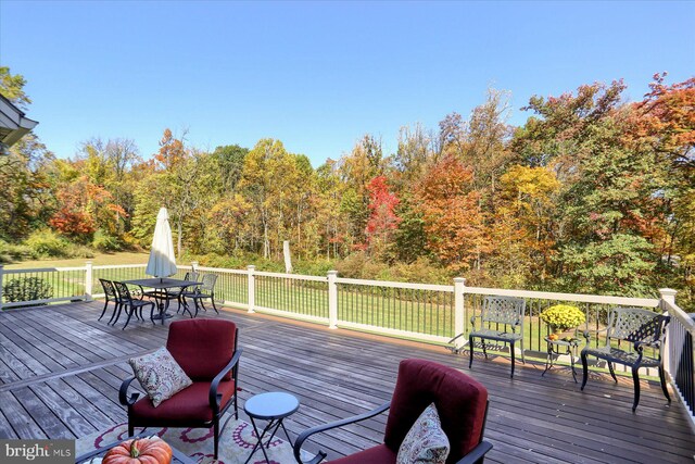 wooden terrace featuring a wooded view and outdoor dining space