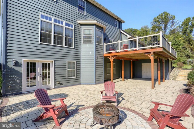 rear view of house with a patio area, a wooden deck, a fire pit, and french doors