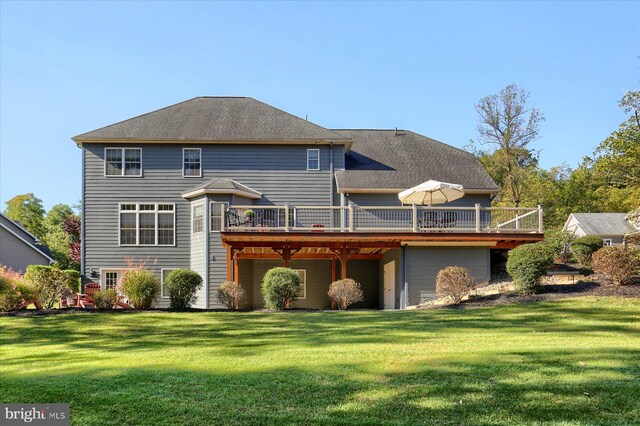 back of house with roof with shingles, a deck, and a yard