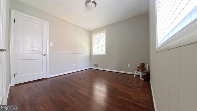 spare room with lofted ceiling, dark wood-type flooring, and a textured ceiling