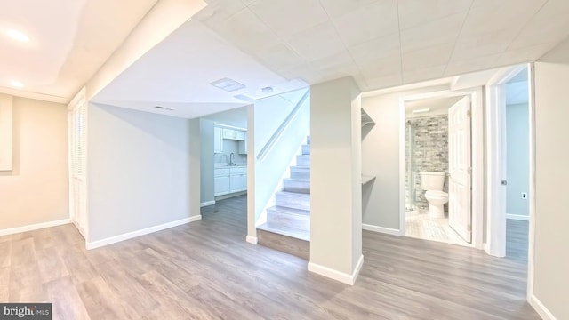 basement featuring sink and light hardwood / wood-style flooring