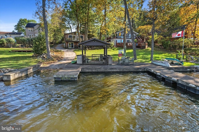 dock area with a gazebo, a water view, and a lawn