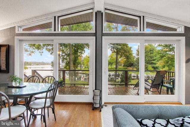doorway to outside with wood finished floors, lofted ceiling with beams, and a water view