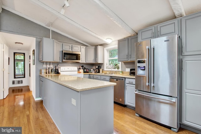 kitchen with vaulted ceiling, a peninsula, gray cabinetry, visible vents, and stainless steel appliances
