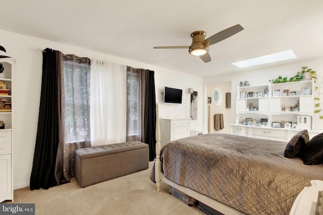 carpeted bedroom featuring a skylight and ceiling fan