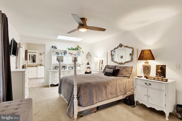 bedroom featuring light carpet, ceiling fan, connected bathroom, and a skylight