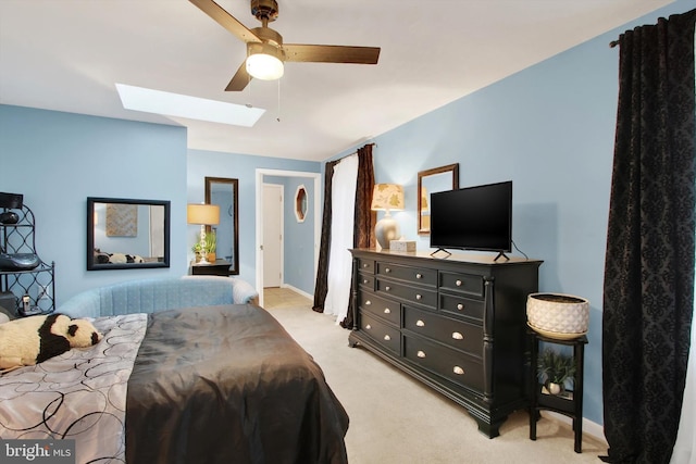 bedroom featuring light carpet, ceiling fan, baseboards, and a skylight