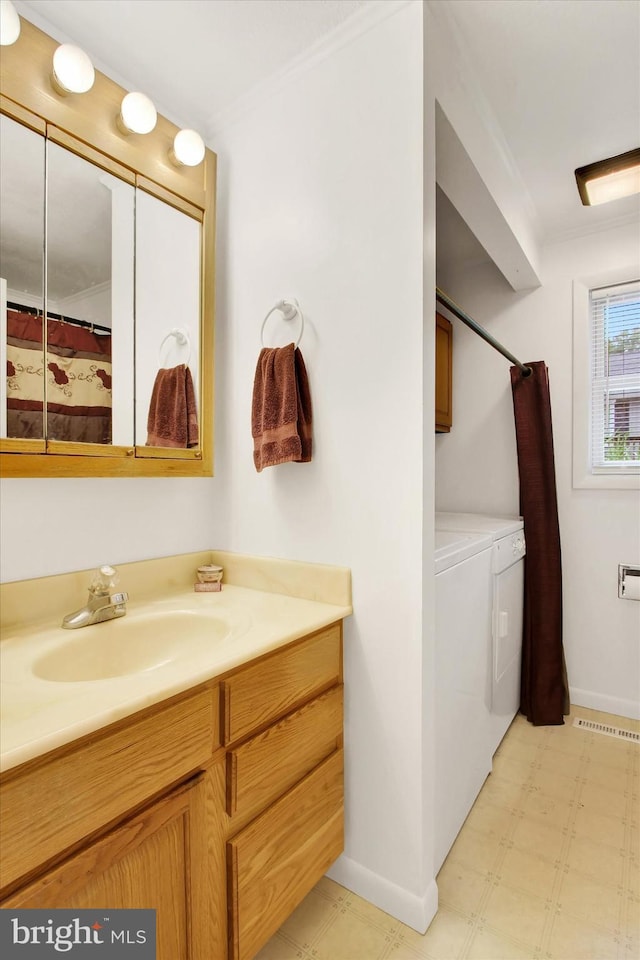 bathroom featuring vanity, baseboards, ornamental molding, tile patterned floors, and washing machine and clothes dryer