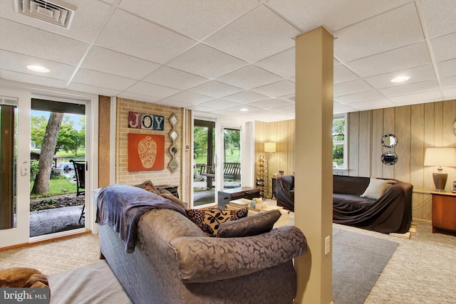 carpeted living area with a paneled ceiling, wood walls, visible vents, and recessed lighting