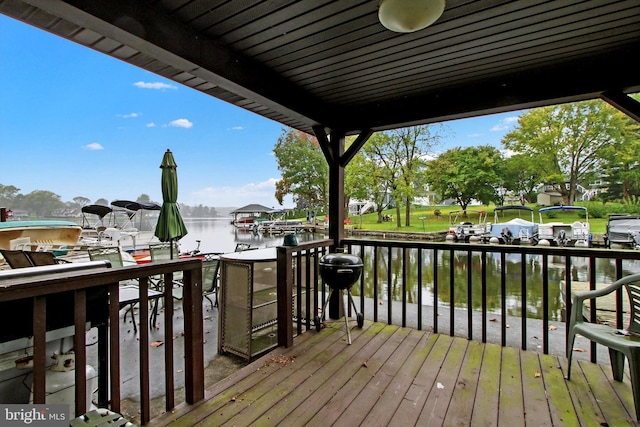 wooden deck with a water view, a grill, and a boat dock