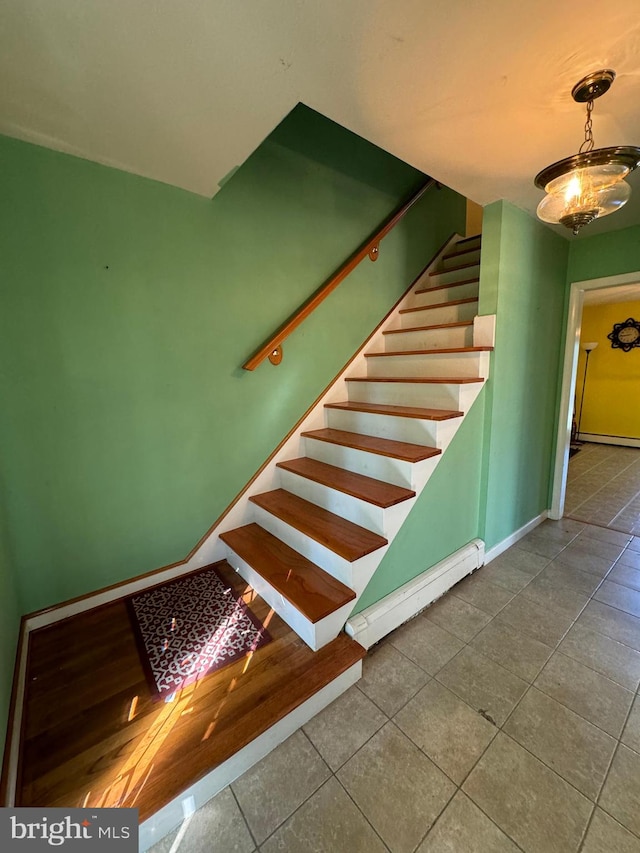 staircase featuring a baseboard heating unit and tile patterned floors