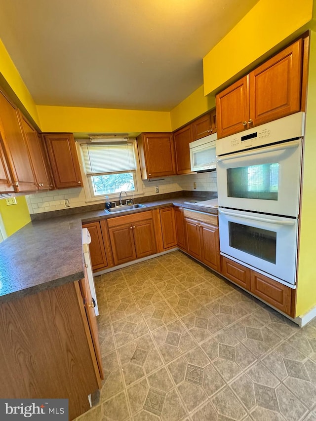 kitchen with sink, light tile patterned floors, backsplash, and white appliances