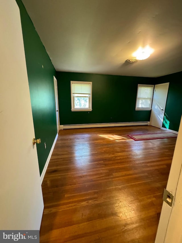 spare room featuring wood-type flooring and plenty of natural light