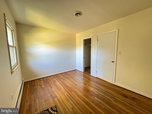 empty room with baseboard heating and hardwood / wood-style flooring