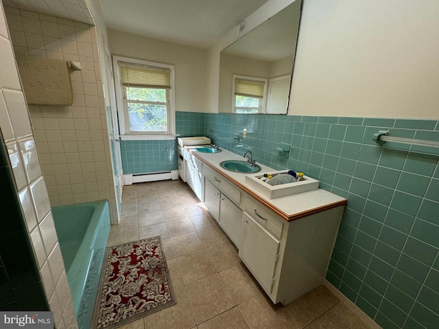 bathroom featuring tile patterned floors, a tub to relax in, a baseboard radiator, tile walls, and vanity