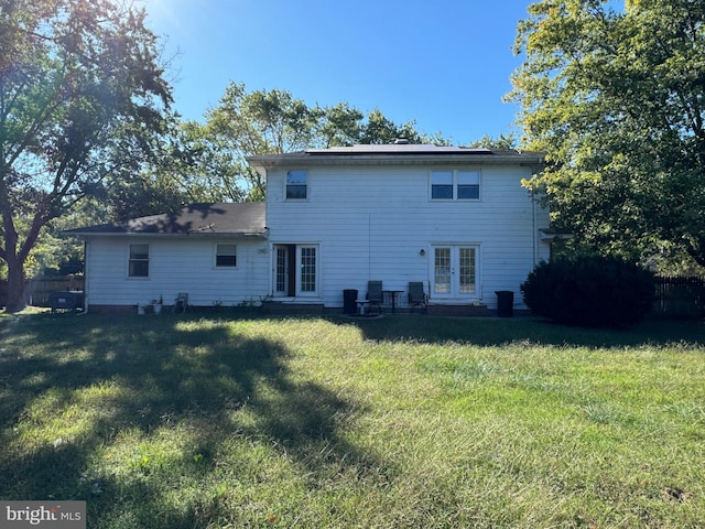 rear view of property featuring french doors and a lawn