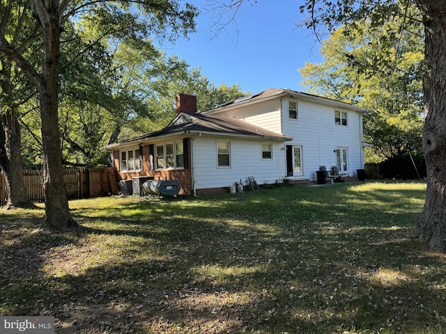 rear view of house featuring central AC and a yard