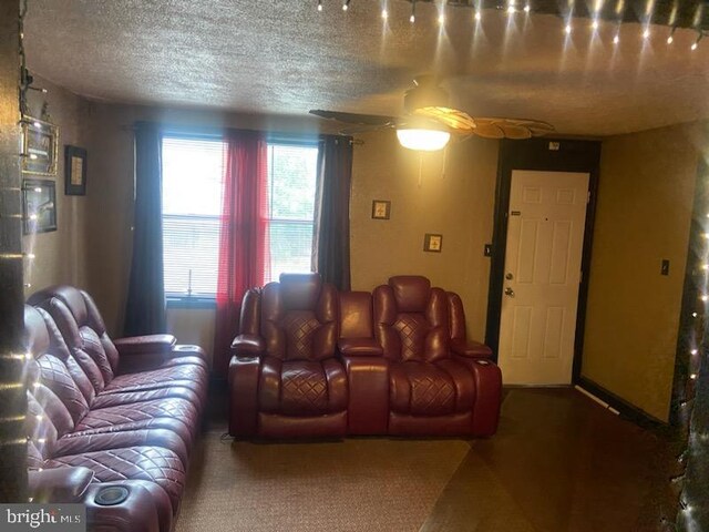 living room with ceiling fan and a textured ceiling