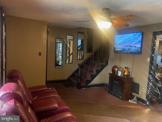 carpeted living room featuring ceiling fan and a textured ceiling