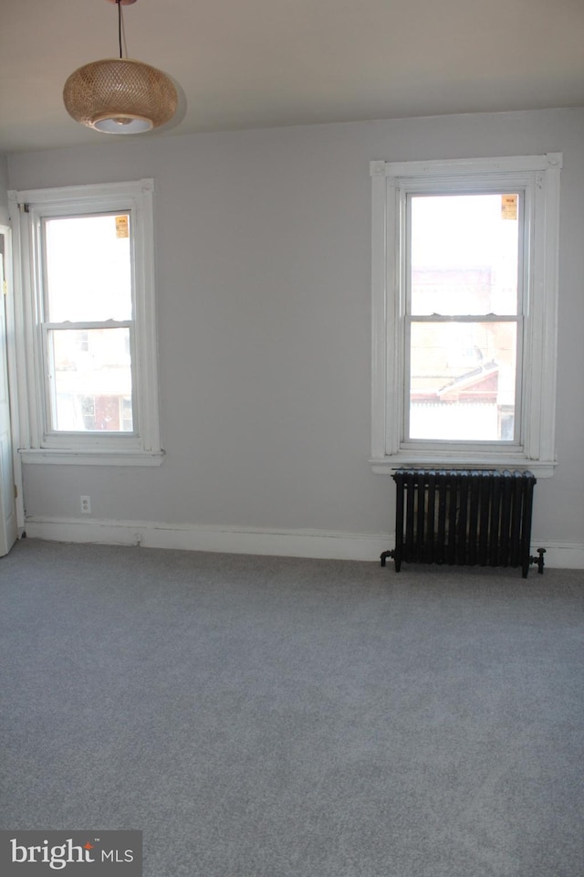 carpeted empty room featuring radiator heating unit