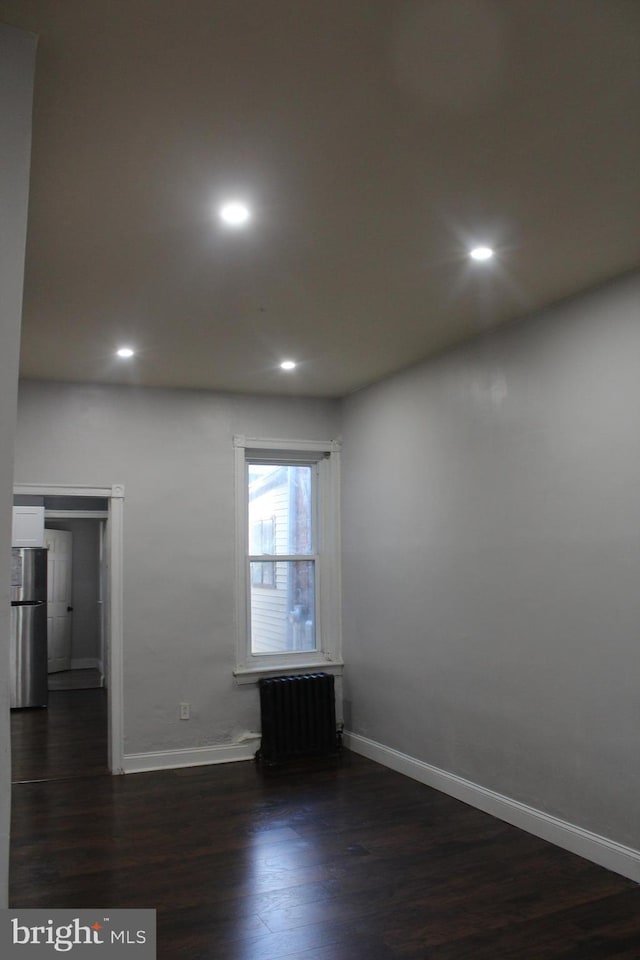 spare room with radiator and dark hardwood / wood-style floors