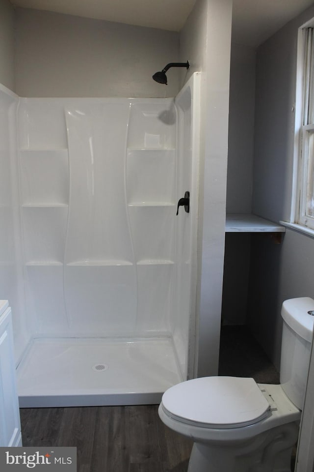 bathroom with wood-type flooring, walk in shower, and toilet