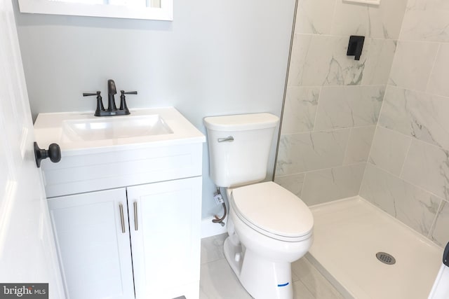 bathroom featuring a tile shower, vanity, and toilet