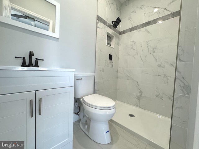 bathroom featuring toilet, vanity, and tiled shower