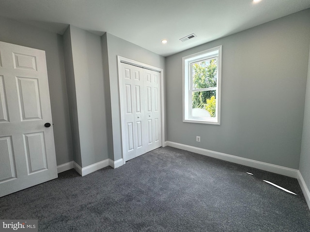 unfurnished bedroom featuring dark carpet and a closet