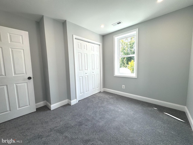 unfurnished bedroom featuring dark carpet and a closet