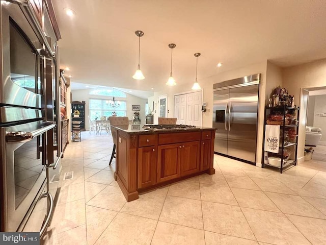 kitchen featuring pendant lighting, dark stone counters, a center island, a breakfast bar area, and stainless steel appliances