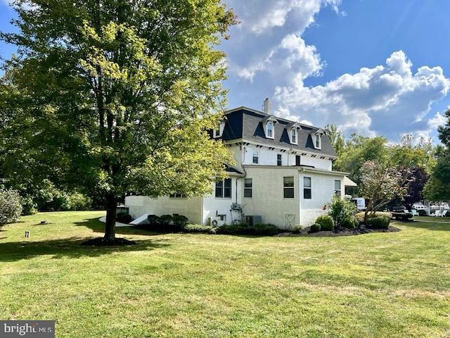 view of side of home featuring a yard and central AC