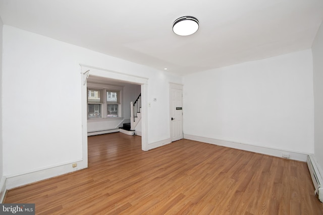 empty room with a baseboard heating unit and hardwood / wood-style floors