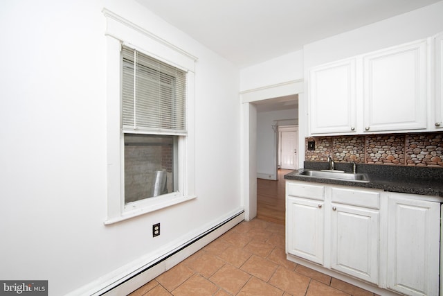 kitchen featuring white cabinets, sink, a baseboard heating unit, and tasteful backsplash