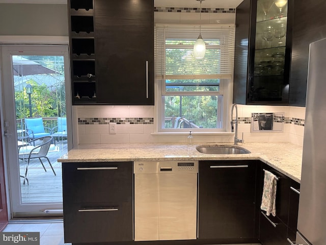 kitchen featuring backsplash, light stone counters, a healthy amount of sunlight, and stainless steel dishwasher