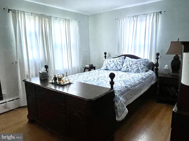 bedroom featuring hardwood / wood-style floors and a baseboard heating unit