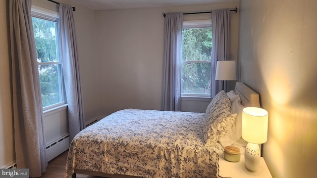 bedroom featuring a baseboard heating unit and dark hardwood / wood-style floors