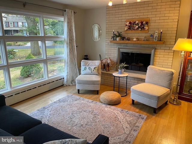 living room featuring hardwood / wood-style flooring, a fireplace, a baseboard radiator, and a wealth of natural light