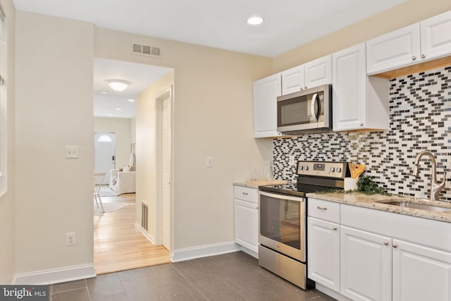 kitchen featuring white cabinetry, light stone counters, stainless steel appliances, dark hardwood / wood-style floors, and sink