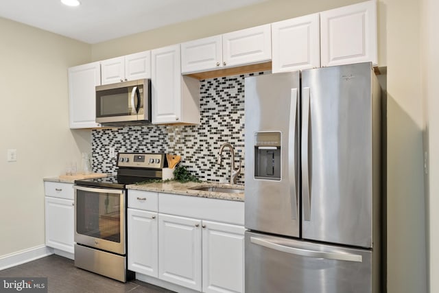 kitchen featuring backsplash, sink, stainless steel appliances, and white cabinets