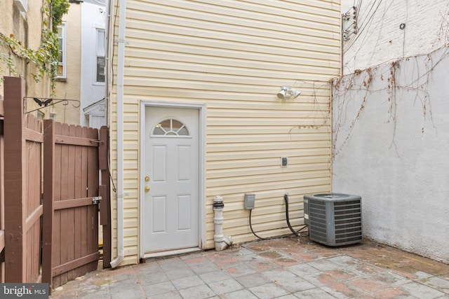 view of exterior entry with central AC and a patio area