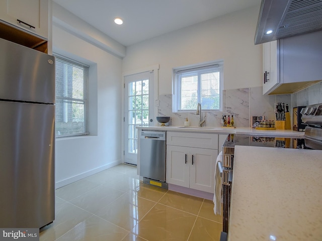 kitchen with tasteful backsplash, stainless steel appliances, sink, light tile patterned floors, and white cabinets