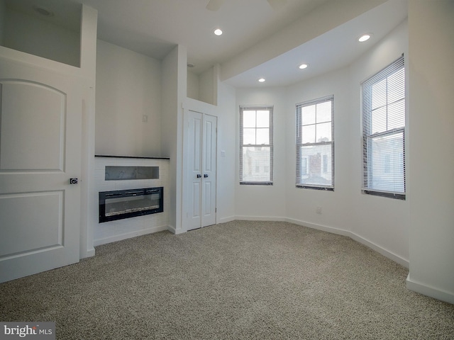 unfurnished living room featuring carpet and ceiling fan