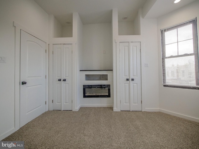 unfurnished living room with carpet and a tile fireplace