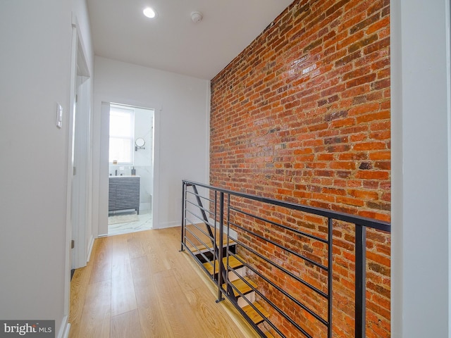 hall with light hardwood / wood-style flooring and brick wall