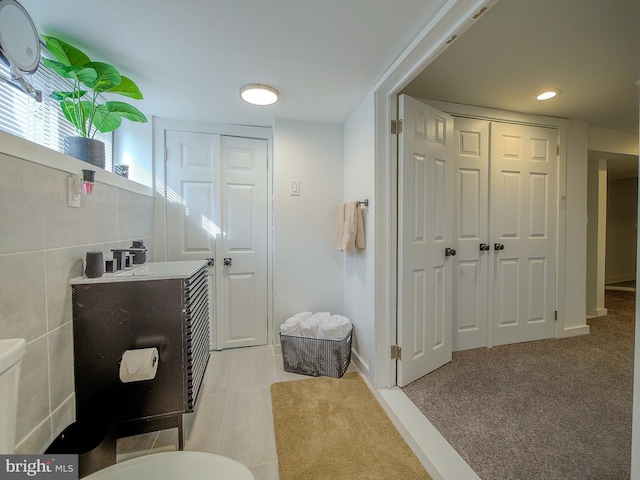 bathroom featuring sink, tile walls, and toilet