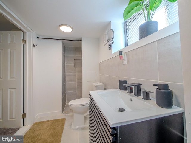 bathroom featuring tile patterned flooring, vanity, toilet, and tile walls