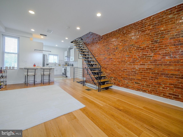 stairs featuring hardwood / wood-style floors, sink, and brick wall