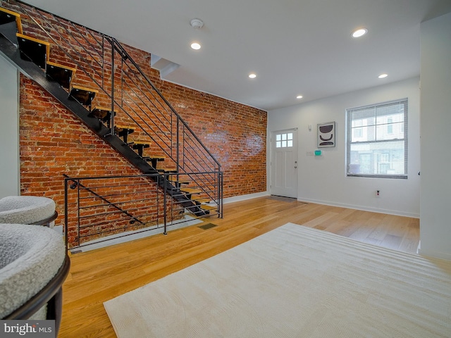 entryway with brick wall and wood-type flooring